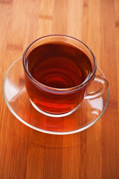 Pohár (čaj, káva) proti dřevěný stůl — Stock fotografie