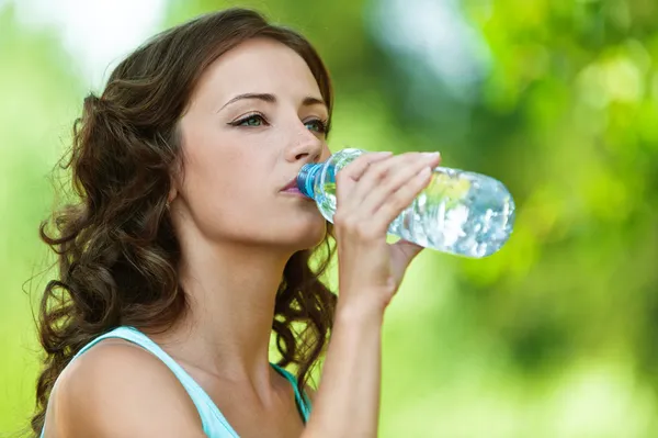 Молодая темноволосая женщина пьет воду — стоковое фото