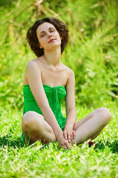 Menina senta-se no gramado — Fotografia de Stock