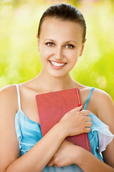 Retrato de una mujer sosteniendo un libro en el parque verde de verano — Foto de Stock