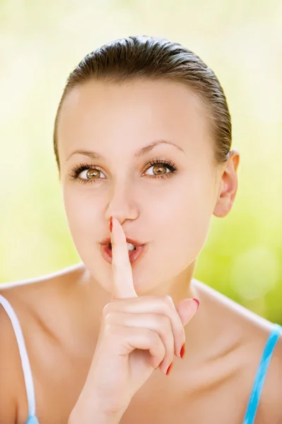 Retrato mujer joven sosteniendo el dedo cerca de los labios — Foto de Stock