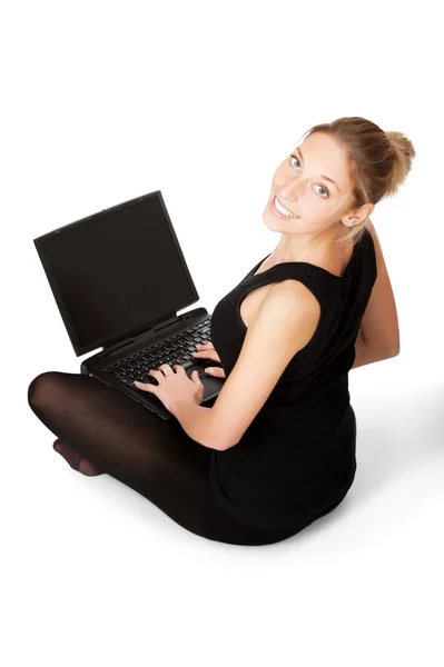 微笑永女人坐在地板上用隔离对惠特的笔记本电脑 免版税图库图片