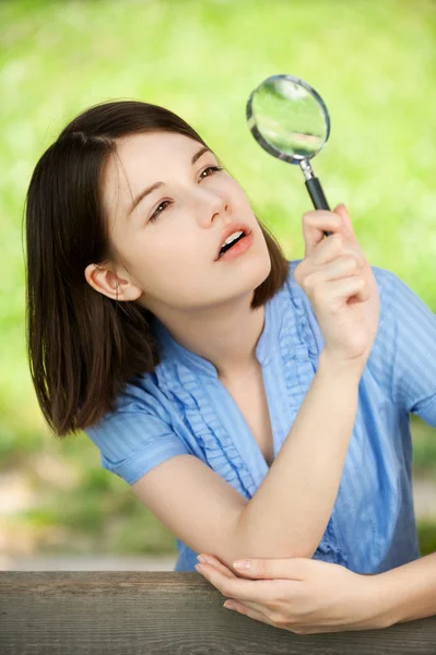 Young woman looks through magnifier Royalty Free Stock Images