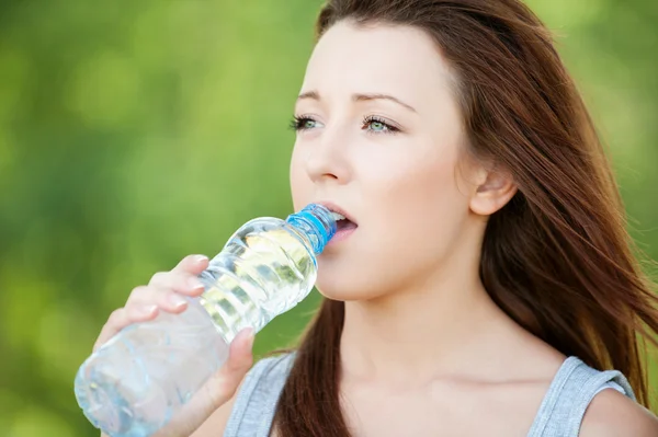 Joven mujer bebiendo botella de agua — Foto de Stock