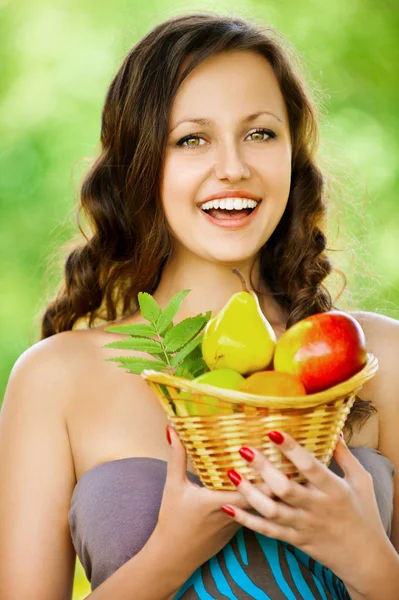 Mujer joven sosteniendo una cesta de fruta — Foto de Stock