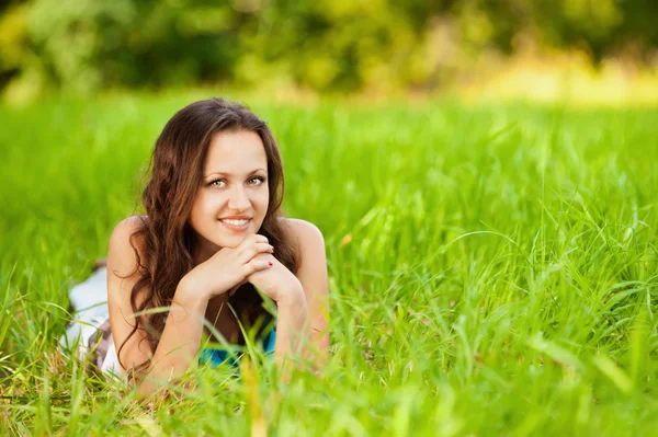 Krásný mladý usmívající se žena leží zelené trávy — Stock fotografie