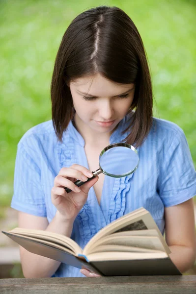 Young woman close-up reading book magnifier — Stock Photo, Image