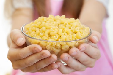 Little girl holding bowl with pasta clipart