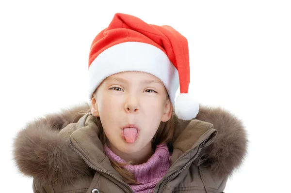 Маленька дівчинка в різдвяному капелюсі показує язик — стокове фото
