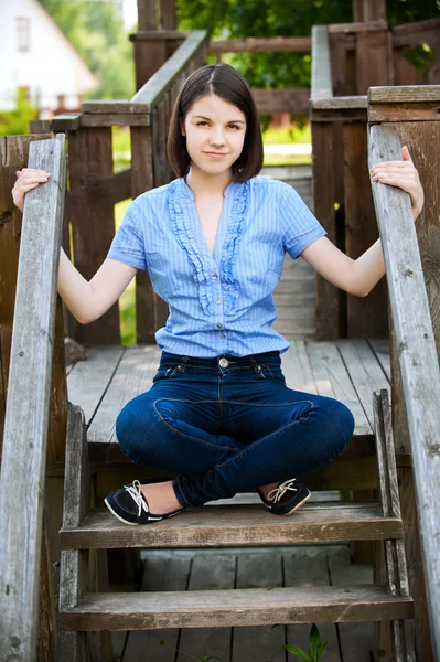 Молода жінка сидить на дерев'яних драбинах — стокове фото