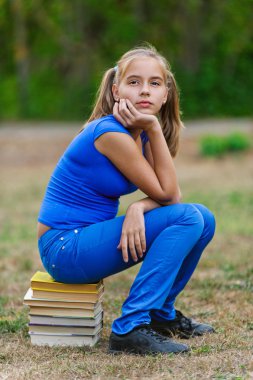 Teenager girl sitting on stack books clipart