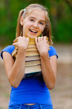 Teenager girl holding stack of seven books clipart