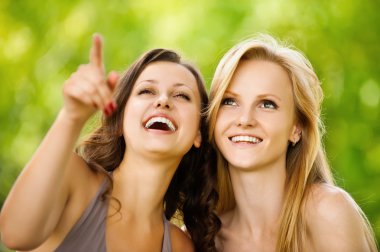 Two youngl pretty women in a park clipart