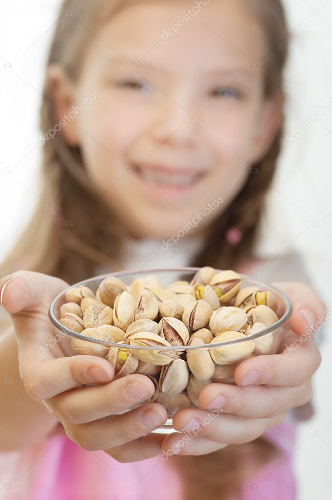 Little girl holding bowl with pistachios