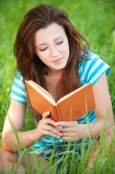 Młoda kobieta siedzi na trawie i czytanie książki — Zdjęcie stockowe