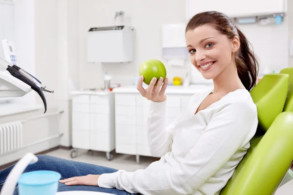 Uma menina com uma maçã na odontologia — Fotografia de Stock