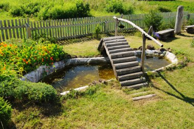 Small garden pond with wooden bridge clipart