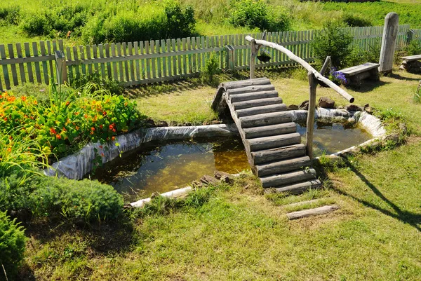 Pequena lagoa de jardim com ponte de madeira — Fotografia de Stock