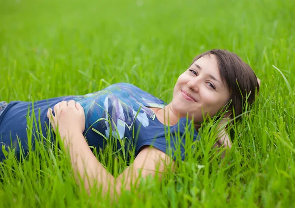 Jeune femme relaxant sur l'herbe verte — Photo