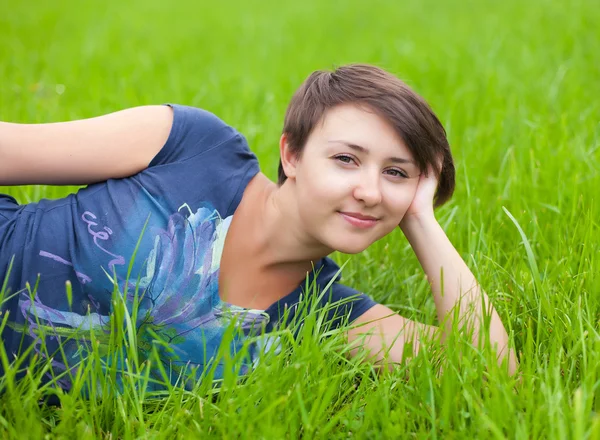 Relaxační na zelené trávě mladá žena — Stock fotografie