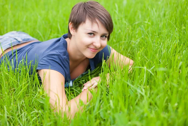 Ung kvinde slapper af på det grønne græs - Stock-foto