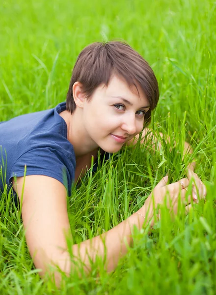 Ung kvinde slapper af på det grønne græs - Stock-foto