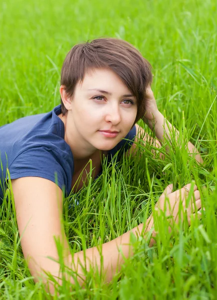 Relaxační na zelené trávě mladá žena — Stock fotografie