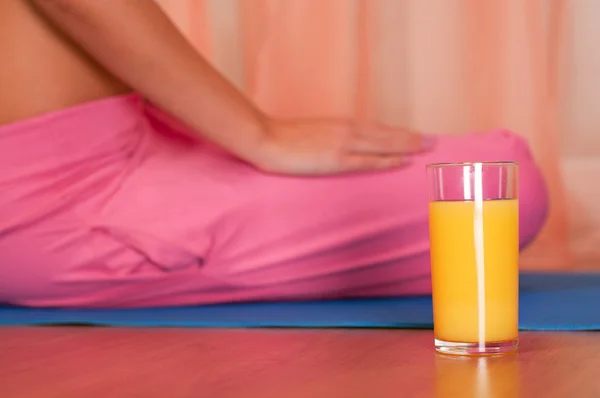 Vaso de zumo de naranja frente a mujer deportiva — Foto de Stock