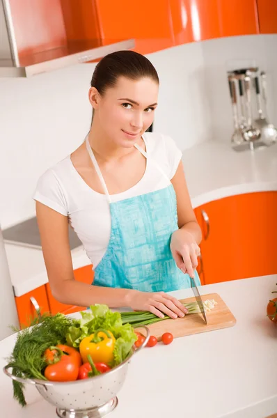 Giovane donna che taglia verdure in una cucina — Foto Stock