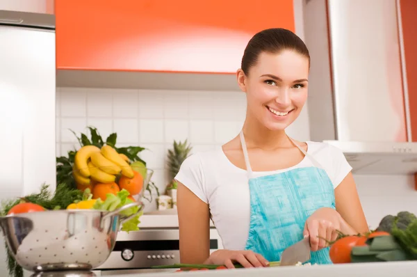 Młoda kobieta krojenie warzyw w kuchni — Zdjęcie stockowe