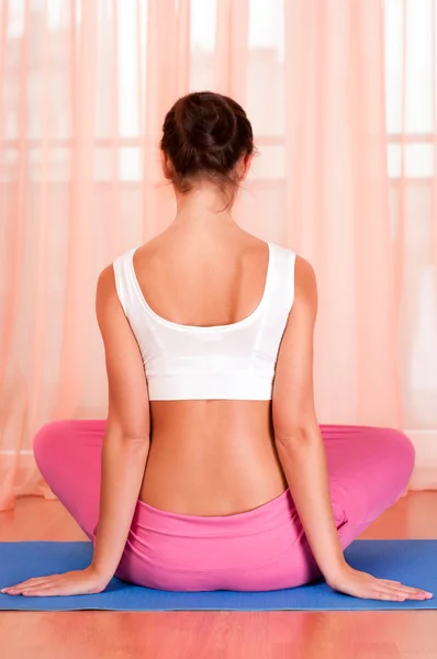 Гарненька молода жінка займається вправами йоги на килимку — стокове фото