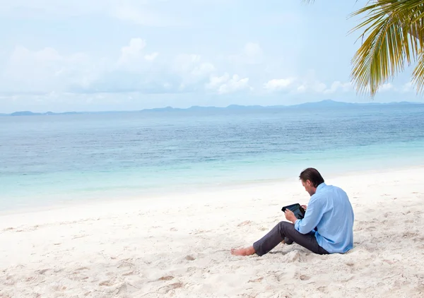 Affärsman sitta och arbeta på stranden med ipad — Stockfoto