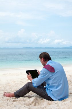 tablet yüklü ile sahilde çalışma ve oturma iş adamı