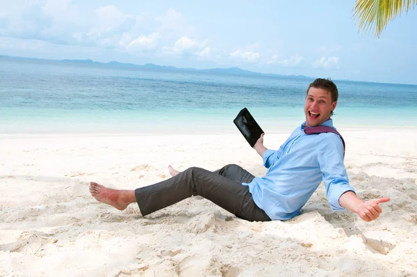 Счастливый бизнесмен сидит и работает на пляже с планшетом — стоковое фото