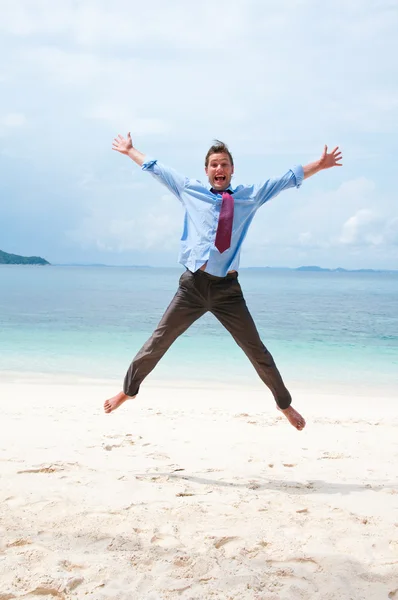 Grappige bedrijf man springen op het strand — Stockfoto