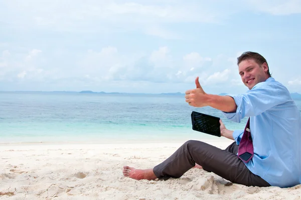 Бизнесмен, сидящий и работающий на пляже с планшетным компьютером — стоковое фото