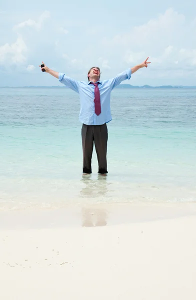 Funny business man ringer genom mobilen på stranden — Stockfoto