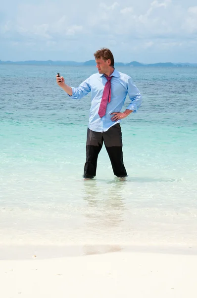 Деловой человек звонит по мобильному телефону на пляже — стоковое фото