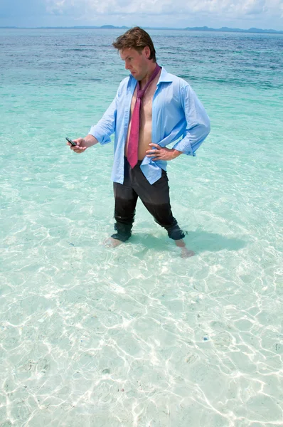 搞笑业务人在海滩上调用通过手机 — 图库照片