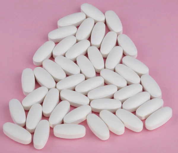 A rózsaszín háttér, fehér tabletta — Stock Fotó