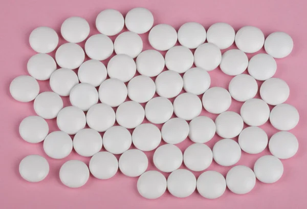 Białe tabletki na różowym tle — Zdjęcie stockowe
