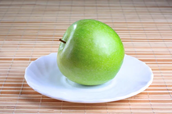 Green apple on the saucer — Stock Photo, Image