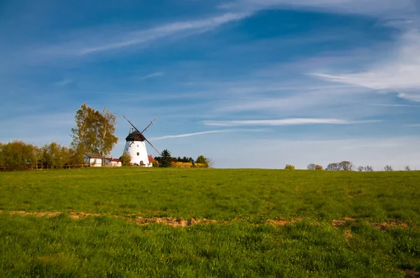 stock image White windmill on the green farm field