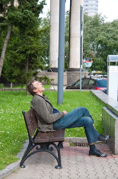 Hajléktalan részeg ember alszik a padon forró nap — Stock Fotó