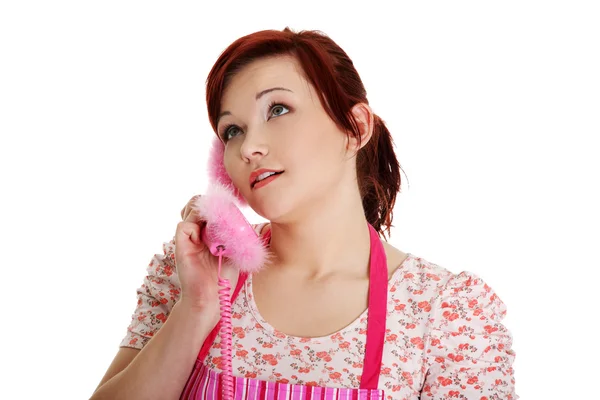 Szczęśliwa kobieta w różowym fartuchu mówi przez telefon. — Zdjęcie stockowe