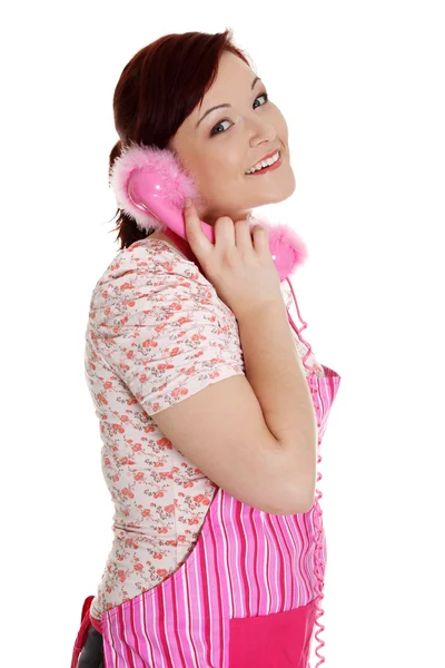 Happy woman in pink kitchen apron talking on the phone. — Stock Photo, Image