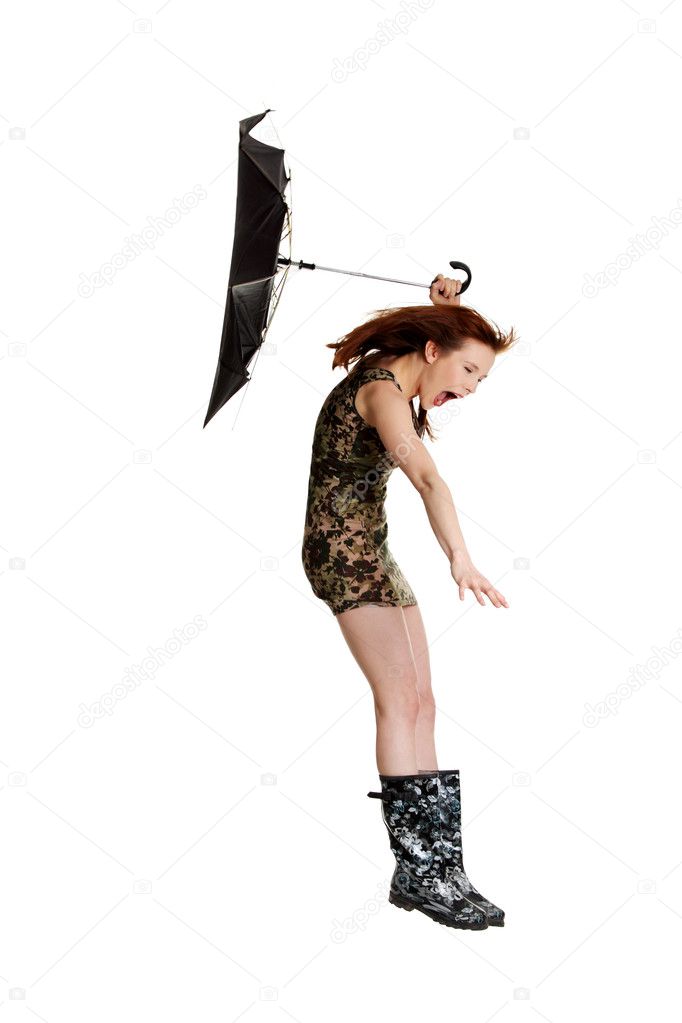 Young woman with umbrella blown by wind.