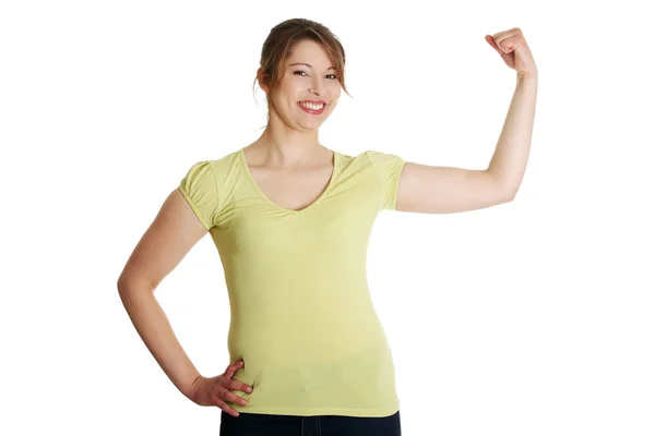 Słodkie młoda kobieta uśmiechający się pokazano jej biceps — Zdjęcie stockowe