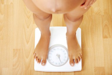 Pregnant woman standing on the scales. clipart