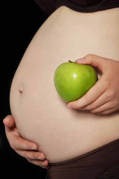 Pancia di una donna incinta con mela verde — Foto Stock